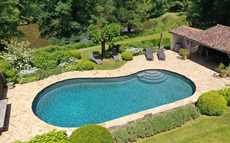 Luxe Vakantiehuis Dordogne - Zwembad en tuin Gezicht op het privézwembad van een luxe vakantiehuis in Dordogne, omgeven door groene tuin en comfo.