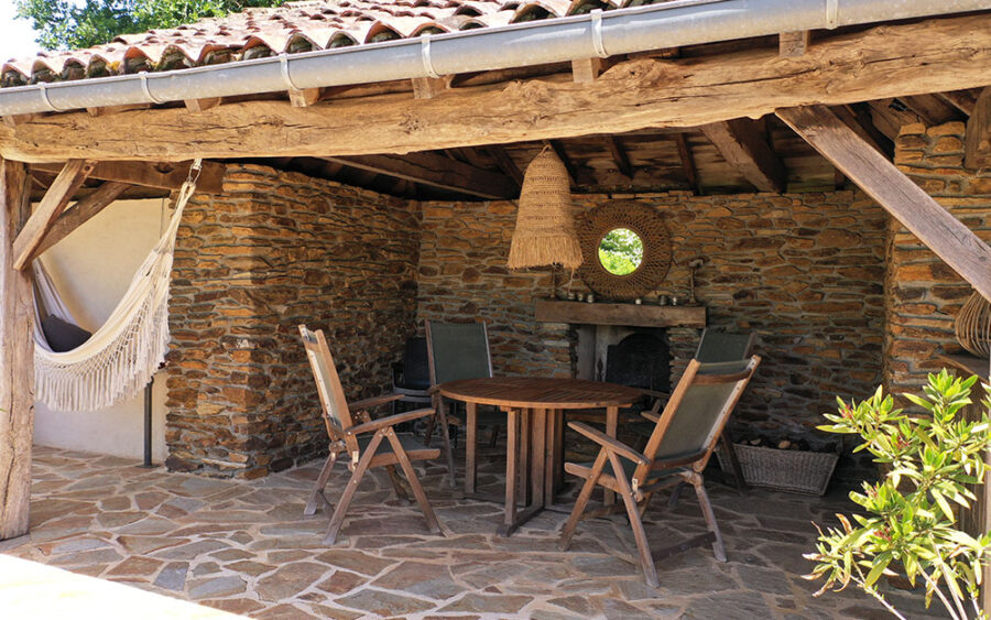 Luxe Vakantiehuis Dordogne - Buitenruimte Gezellige buitenruimte met eettafel en stoelen onder een houten overkapping in Dordogne. Perfect voo.