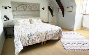 Luxe slaapkamer in Dordogne met bloemenbed en rustieke details.