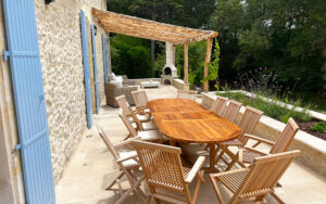 Uitzicht op terras met houten tafel en stoelen bij luxe vakantiehuis.