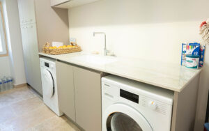 Luxe wasruimte met wasmachine en opbergkasten Luxe wasruimte met wasmachine, opbergkasten en wastafel in moderne woning.
