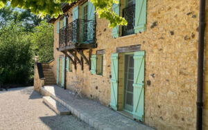 Charming Dordogne Stone Cottage Charming stone cottage in Dordogne with turquoise shutters and a small balcony, surrounded by lush g.