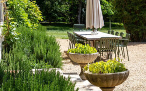 Luxe Vakantiehuis Dordogne tuin Gezellige tuin met tafel, parasol en bloemen in Dordogne.