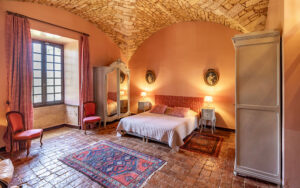 Cozy bedroom with rustic stone walls, vintage furniture, and warm lighting in a Dordogne vacation re.
