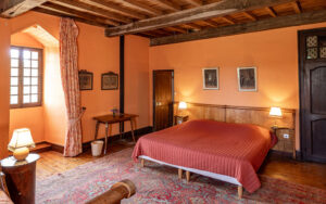 Cozy bedroom with rustic wooden beams and warm decor in Dordogne vacation house.
