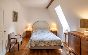 Elegant bedroom with natural light and rustic wooden accents in Dordogne vacation rental.