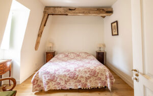 Comfortable bedroom with rustic wooden beam in a Dordogne holiday house. Perfect for a relaxing stay.