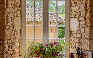Authentic stone window with white frame overlooking lush greenery in Dordogne.