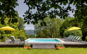 Swimming pool with sun loungers and umbrellas in scenic Dordogne.