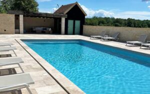Zwembad van luxe vakantiehuis in Dordogne met terras en ligbedden.
