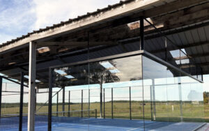 Modern glass-enclosed sports court in a Dordogne luxury holiday home with scenic countryside views.