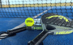 High-quality paddle and tennis rackets with bright yellow ball on court for outdoor sports at luxury Dordogne holiday home.