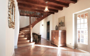 Bright interior of luxury Dordogne vacation home with wooden staircase and rustic decor.