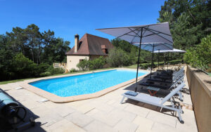 Luxe vakantiehuis in Dordogne met privézwembad en ligstoelen in de tuin.