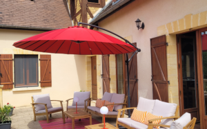 Gezellige buitenruimte met tuinmeubilair en parasol in luxe vakantiehuis Dordogne.