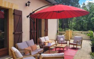 Gezellige buitenruimte met comfortabele tuinmeubels, grote parasol en uitzicht op groene omgeving in.
