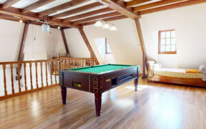 Bright loft with pool table and cozy bed in Dordogne vacation home.