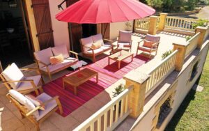 Luxe terras met comfortabele tuinmeubels, grote parasol en kleurrijk tapijt in Dordogne vakantiehuis.