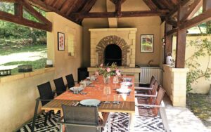 Gezellige buiten eethoek met open haard in een luxe vakantiehuis in Dordogne.