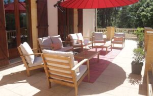 Comfortabele zithoek op terras van luxe vakantiehuis in Dordogne met parasol en tuin.