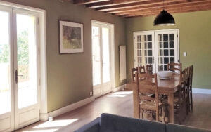 Bright dining area with wooden table and large windows in Dordogne holiday house.