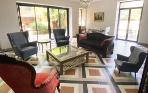 Luxe woonkamer met comfortabele stoelen en grote ramen in vakantiehuis Dordogne, perfect voor ontspa.