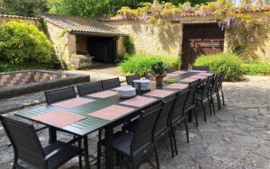 Buiten eettafel met 12 stoelen in de tuin van een luxe vakantiehuis in Dordogne, omgeven door groen.