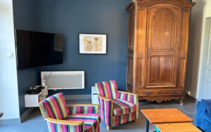 Gezellige woonkamer in luxe vakantiehuis Dordogne met kleurrijke gestreepte stoelen, grote houten ka.
