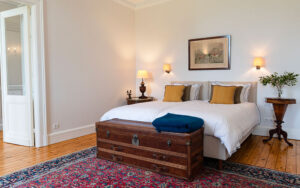Luxe slaapkamer met antieke kist, beddengoed en wandlampen in Dordogne.