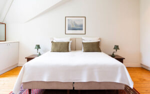 Luxe slaapkamer met wit bed en groene kussens in Château de Bel Air.