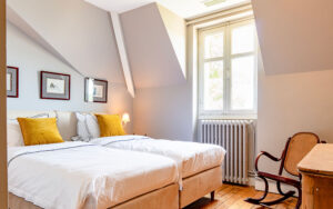 Knusse slaapkamer in een luxe vakantiehuis in Dordogne met tweepersoonsbed en vintage stoel.
