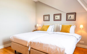 Luxe slaapkamer in Dordogne vakantiehuis met wit bed en gele kussens.
