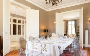 Elegant eetkamer in luxe vakantiehuis met chandelier en grote ramen.