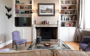 Gezellige woonkamer in luxe vakantiehuis met open haard en boekenplanken.