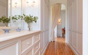 Elegante witte corridor met houten vloer en decoratieve planten.