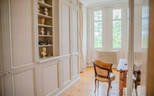 Gezellig interieur met grote ramen, houten vloer en klassieke meubels.