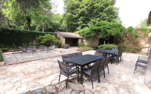 Buitenruimte van luxe vakantiehuis met tuinmeubilair en open haard.
