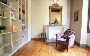 Knusse woonkamer met vintage fauteuil en grote boekenkast.