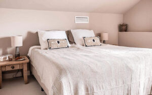 Luxe Vakantiehuis Dordogne slaapkamer Luxe slaapkamer in Dordogne vakantiehuis met wit beddengoed en decoratieve kussens.
