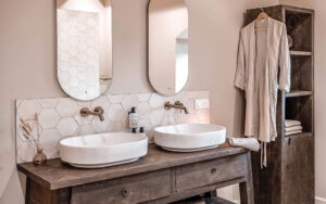 Luxe badkamer in Domaine Lèisa Moderne badkamer met dubbele wastafels en grote spiegels in luxe vakantiehuis.